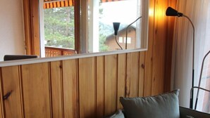 Un mur lambrissé en bois, avec une fenêtre, une lampe et un canapé agrémenté de coussins.