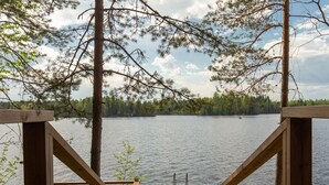 Una terraza de madera con vistas a un lago y un bosque.