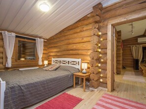 Een slaapkamer in een blokhut met een bed, nachtlampjes en een wandlamp.