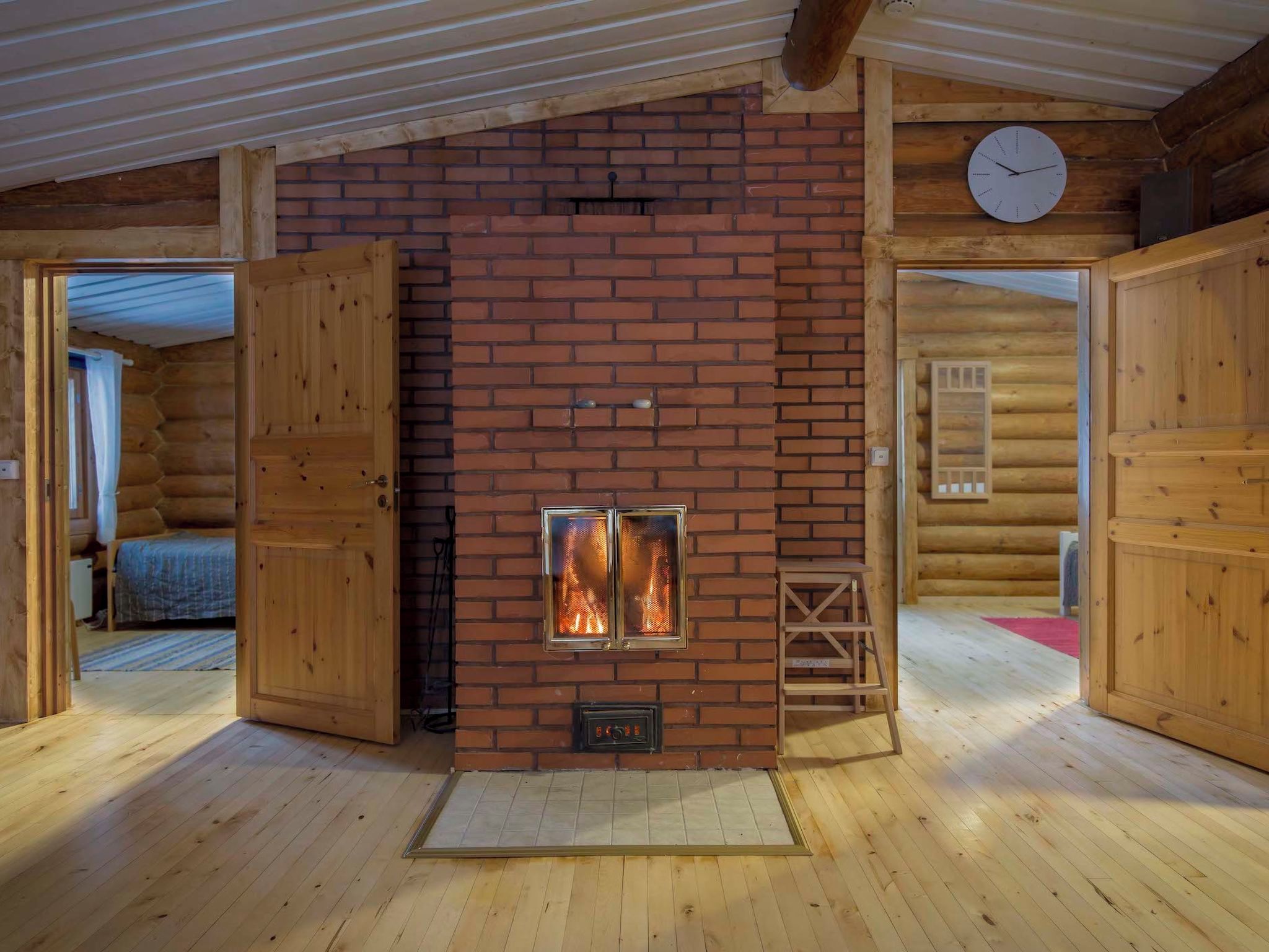 L’intérieur d’une cabane en rondins, avec une cheminée, des murs en bois et une horloge au mur.