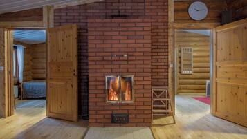L’intérieur d’une cabane en rondins, avec une cheminée, des murs en bois et une horloge au mur.