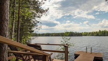 Une terrasse en bois, dotée de bancs, qui offre une vue sur un lac paisible, le tout entouré d’arbres.