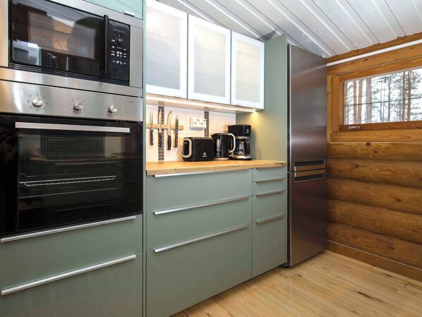A modern kitchen with stainless steel appliances, wooden cabinets, and a window with a view of trees.