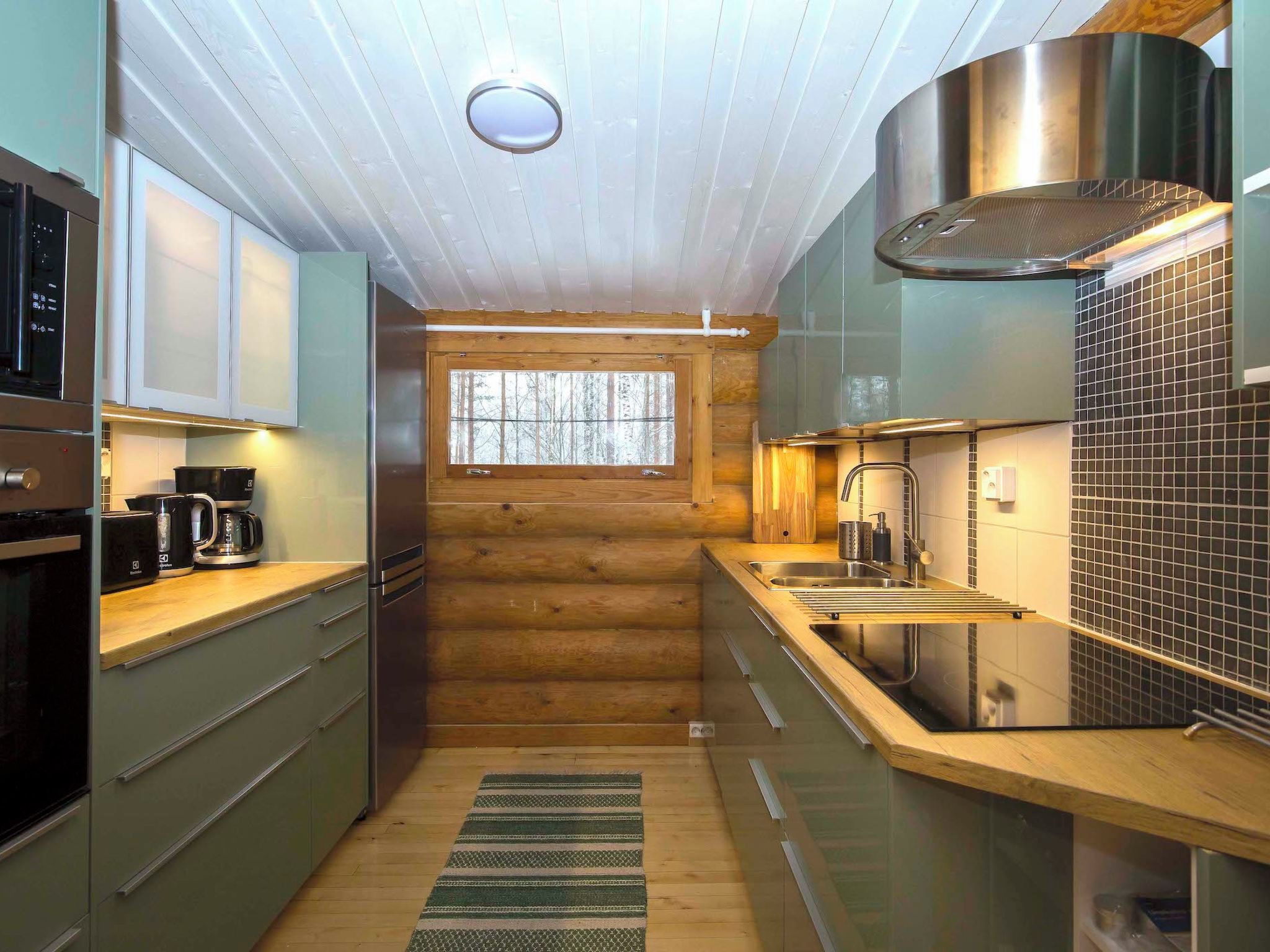 A modern kitchen with wooden accents, stainless steel appliances, and a view through a window.