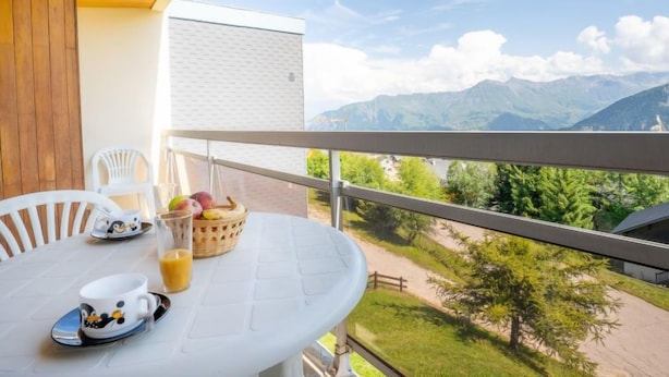 A balcony with a table set for breakfast, overlooking a mountainous landscape.
