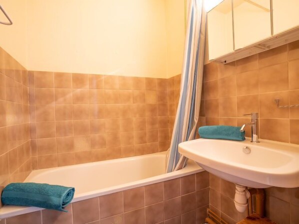 Un baño con bañera, lavamanos y cortina de ducha.