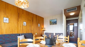 A wooden interior with a dining table set for four, a sofa, and a fireplace.