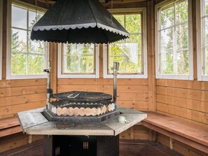 L'intérieur d'un chalet en bois, avec une table centrale, des bancs et une grande fenêtre.