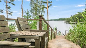 A wooden deck with benches overlooking a calm lake, surrounded by trees.