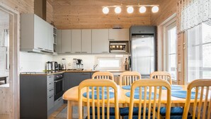 Una cocina compacta con armarios de madera, un microondas, un refrigerador y un comedor con una mesa y sillas de madera.