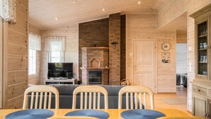 Un interior de madera con comedor, chimenea y televisor.