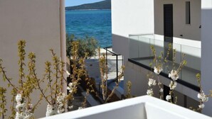 A modern building with a balcony overlooking a clear blue sea and a hilly landscape. - Apartment Ena by Interhome (Brodarica)