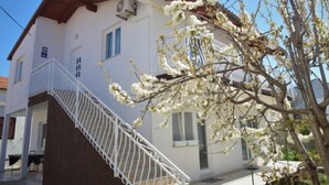 A two-story building with a white exterior, a brown roof, and a white staircase leading to the entrance. - Apartment Ena by Interhome (Brodarica)