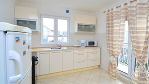 A compact kitchen with a refrigerator, microwave, and sink. - Apartment Ena by Interhome (Brodarica)