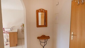 A hallway with a wooden door, a mirror on the wall, and a small table with a stool. - Ardévine 5 by Interhome (Ovronnaz)