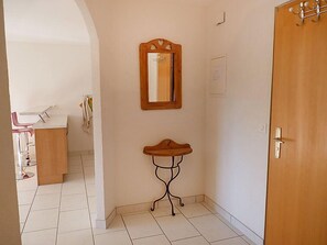 A hallway with a wooden door, a mirror on the wall, and a small table with a stool. - Ardévine 5 by Interhome (Ovronnaz)