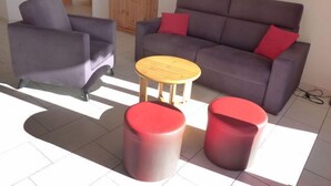 A living room with a grey sofa, two armchairs, a wooden coffee table, and two red ottomans. - Ardévine 5 by Interhome (Ovronnaz)