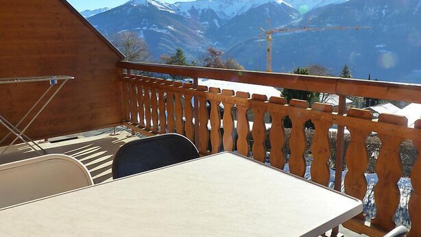 A balcony with a table and chairs, overlooking snow-capped mountains. - Ardévine 5 by Interhome (Ovronnaz)
