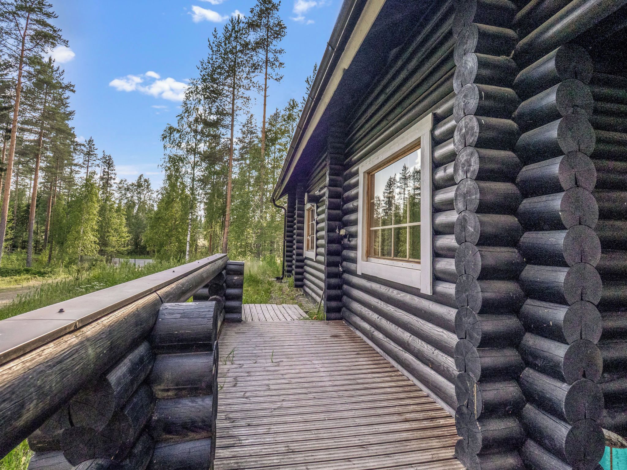 A log cabin with a wooden deck leading to a window.