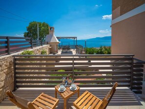 A balcony with wooden furniture, a table set with cups and a kettle, and a view of the sea and mountains. - Vacation home Matea by Interhome (Rijeka)