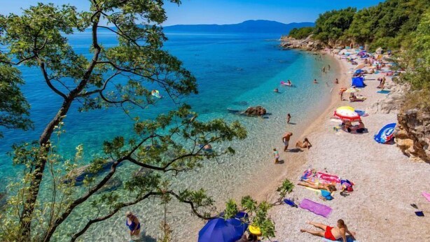 A beach with clear water, people sunbathing, and umbrellas. - Vacation home Matea by Interhome (Rijeka)
