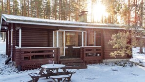 Een chalet met een veranda, een tafel en banken.