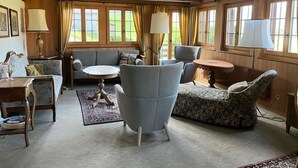Una habitación acogedora con un sofá, sillones, una mesa redonda y una lámpara.