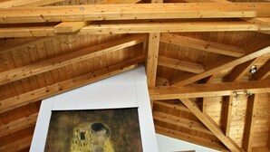 A wooden ceiling with exposed beams and a large painting of a couple. - LuxLax 2. OG Süd by Interhome (Lax)
