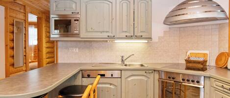 Una cocina compacta con armarios de madera, microondas integrado, estufa y lavamanos.