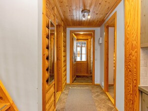 A wooden interior hallway with a door leading to a room.