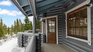 A log cabin with a wooden deck and a large window.