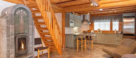Ein gemütliches Blockhaus-Interieur mit Kamin, einer Holztreppe, einer Küchenzeile und einer Sitzecke.