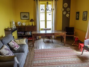 A living room with a sofa, a wooden table, a patterned rug, and a bookshelf. - Les Londes by Interhome (Bayeux)