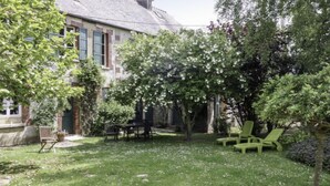 Een huis met een tuin, een terras met stoelen en een gazon.