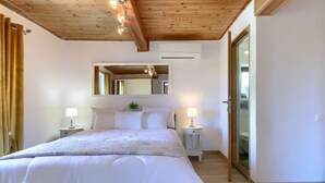 Une chambre à coucher avec un grand lit, deux tables de chevet avec des lampes, un miroir au-dessus du lit et un plafond en bois.