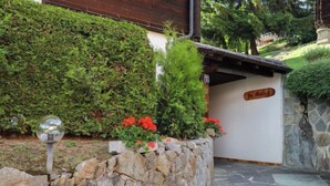 Un chemin de pierres mène à un bâtiment doté d’un toit en bois et d’une enseigne indiquant « Maison d’hôtes ».