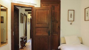 Une chambre avec deux lits, des portes en bois, un couloir et des tableaux encadrés accrochés au mur.