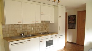 Eine Küche mit weißen Schränken, einer Holz Arbeitsplatte, einem Spülbecken, einem Herd und einem Backofen.