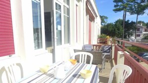 A balcony with a striped table and chairs, a railing, and a view of the street. - Apartment Du lac by Interhome (Hossegor)