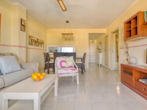 Un salón amplio con un sofá, una mesa de comedor con sillas y un banco blanco.