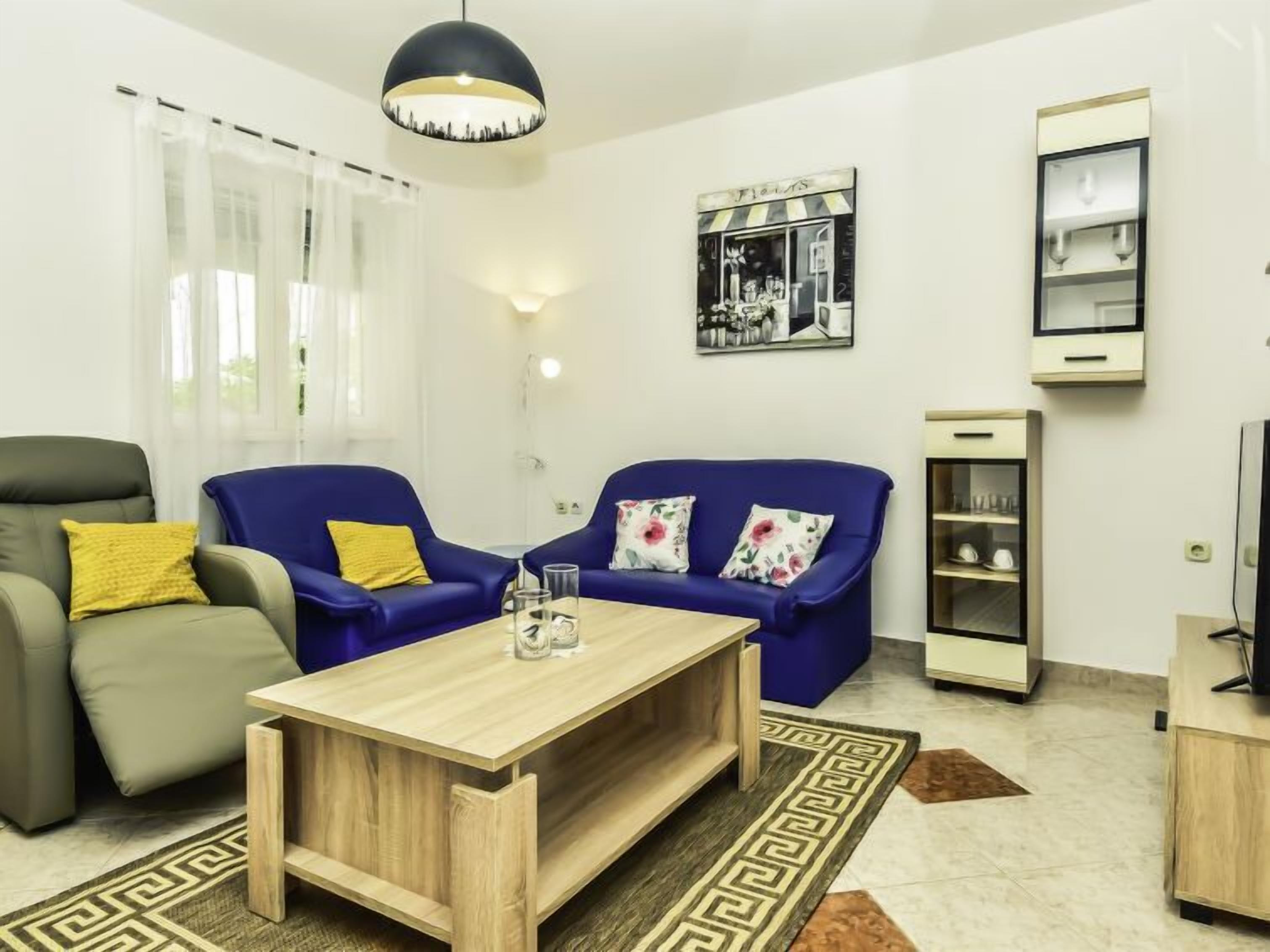 A living room with a sofa, armchair, coffee table, and a painting on the wall.