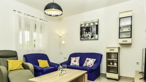 Un salon avec un canapé, un fauteuil, une table basse et un tableau accroché au mur.
