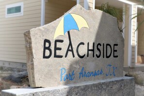A stone sign with the word 'BEACHSIDE' and 'Part Aransas, TX' indicating the location. - Beachside Bungalo (Port Aransas)