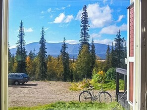 A view of a gravel driveway with a bicycle parked on the right, a car parked on the left, and a mountain range in the background. - Pallaksen valkkorinne by Interhome (Enontekiö)