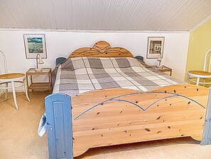 Makuuhuoneessa on puinen sänky, kaksi yöpöytää, tuoli ja kaksi seinälle ripustettua kehystettyä kuvaa.