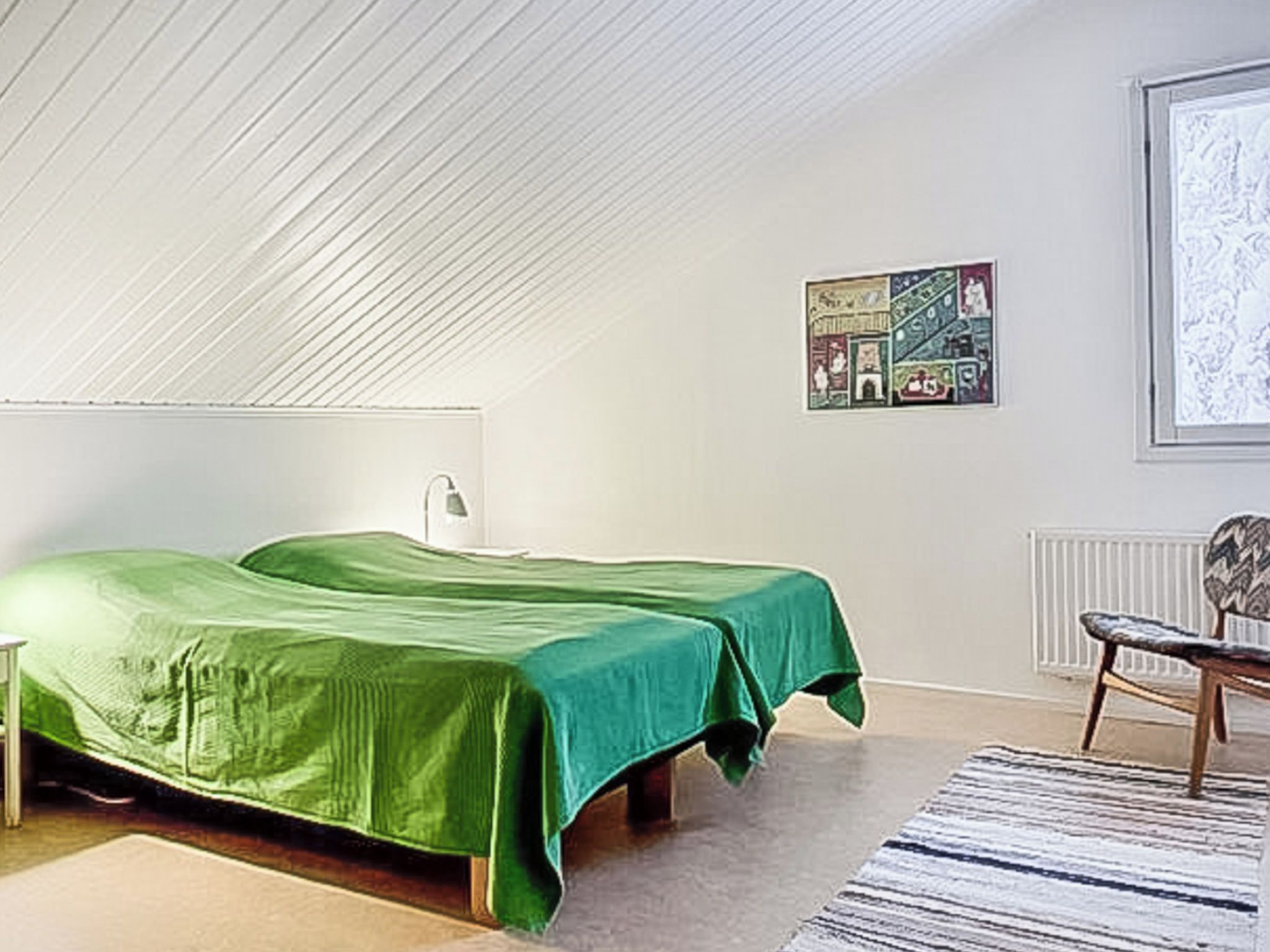 Une chambre avec deux lits, un radiateur, une chaise et un tableau encadré au mur.