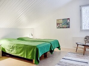 Une chambre avec deux lits, un radiateur, une chaise et un tableau encadré au mur.