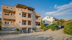 A multi-story building with balconies, a paved courtyard, and surrounding greenery. - Melandura by Interhome (Pag/Dinjiška)