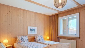 Ett rum med träpanel på väggarna, en säng, ett fönster och en tavla på väggen.