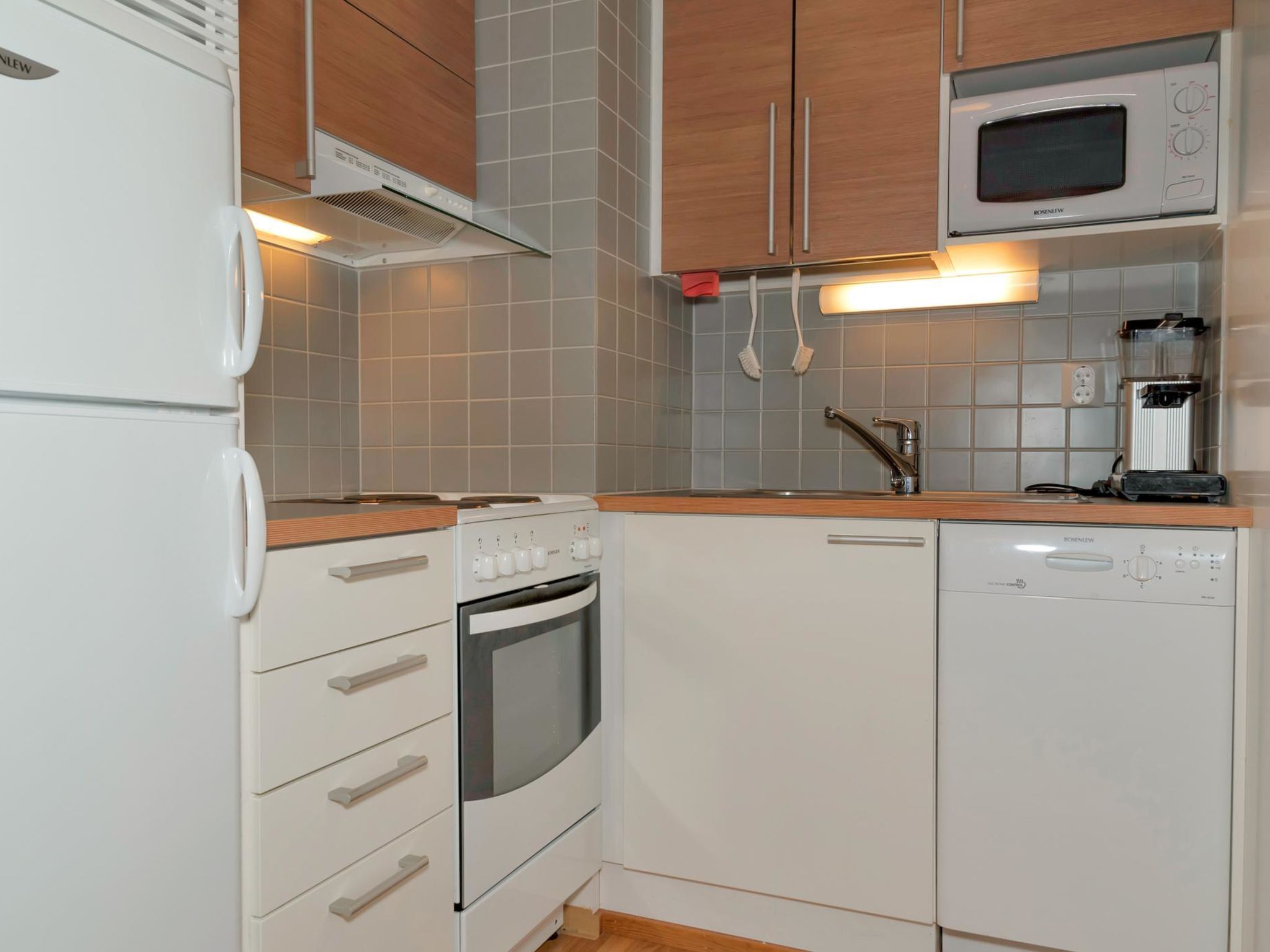 Een koelkast, een magnetron, een vaatwasser, kookgerei, borden en bestek